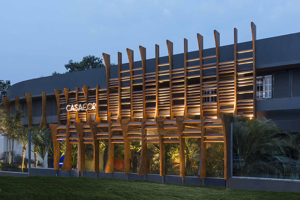 CASACOR Brasília 2016. Fachada Sustentável - Catharina Macedo, Juliana Garrocho, Sheila Beatriz e Roberto Lecomte. Os arquitetos destacam a potência da tecnologia construtiva em madeira laminada colada, com a chancela do WWF-Brasil. Toda a estrutura e o sombreamento combinam madeira industrial e in natura com peças plantadas da Amazônia e árvores nativas. Resíduos de produção madeireira, que são mais curtos, formam a veneziana que protege a fachada da luz solar e das chuvas.