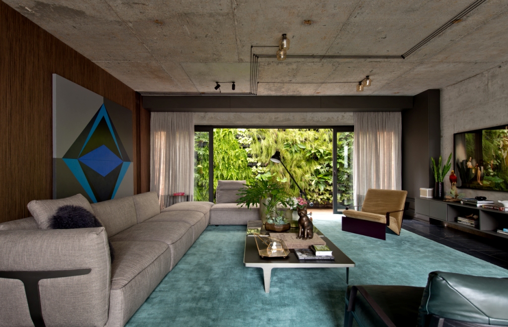 CASACOR Balneário Camboriú 2017. A Sala de Concreto - Moacir Schmitt Jr e Salvio Moraes Jr. Os designers trazem uma paleta de cores neutras como base, em tons acinzentados, até mesmo no uso do concreto aparente. Em contrapartida, escolheram um tom quente, o castor, revestindo algumas paredes em lâmina de madeira natural. Obras de arte e tapeçaria dão outros toques charmosos de cores à ambientação.