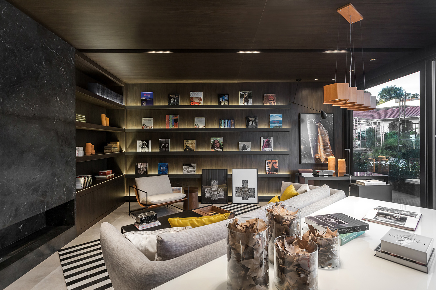 Livraria - Katleen Luizaga. Com o aconchego de uma casa e atmosfera intimista, o espaço convida à leitura. Nas paredes foram aplicados painéis em nogueira, enquanto o piso é um porcelanato com aparência de cimento queimado. Para ficar mais aconchegante, foram escolhidos estofados em couro, linho e veludo. As obras de arte são de Mariana Canet e as cerâmicas, de Denise Coelho.