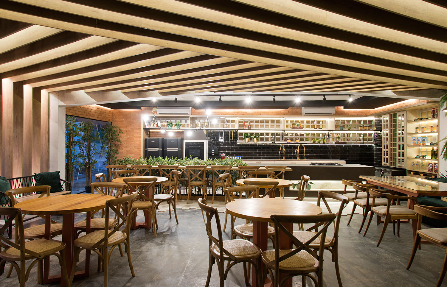 Espaço Gourmet - Marília Mendes. A arte de bem-receber é aplicada através do projeto urbano, arrojado e amplo. O teto, com um suntuoso ripado em madeira garante um efeito visual incrível. O aconchego fica por conta dos grandes sofás verdes. A ilha multiuso é o destaque da área de preparo, com mesa comunal de madeira e ferro fundido, desenhado pela designer.