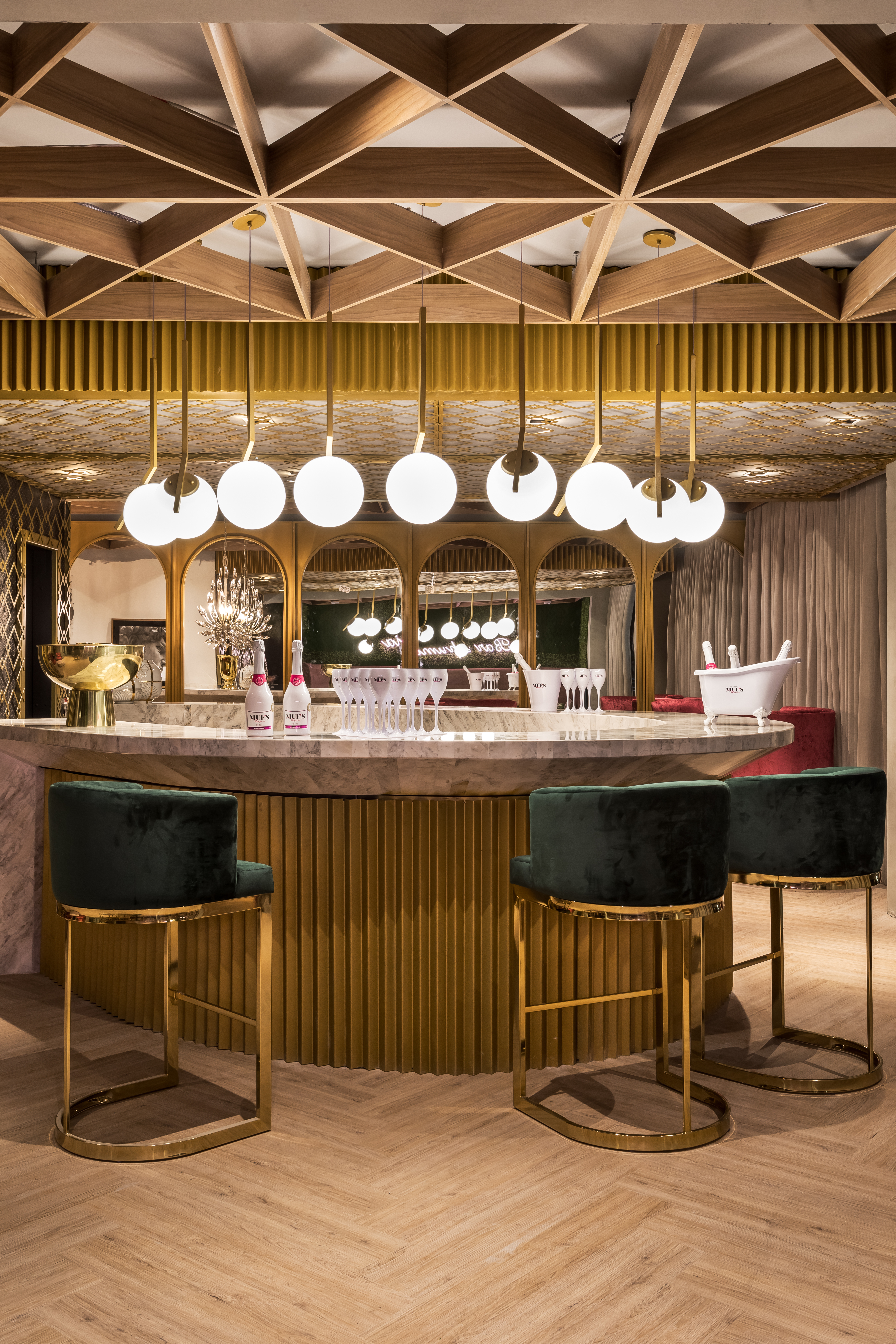 Bar e Espumanteria - Cynthia Karas. Melhor Solução Comercial (júri popular). A proposta é de uma arquitetura sensorial no ambiente de 116 m², com elementos em dourado, espelhos, balcão em mármore e banquetas estofadas em veludo. A madeira ganha destaque no forro.