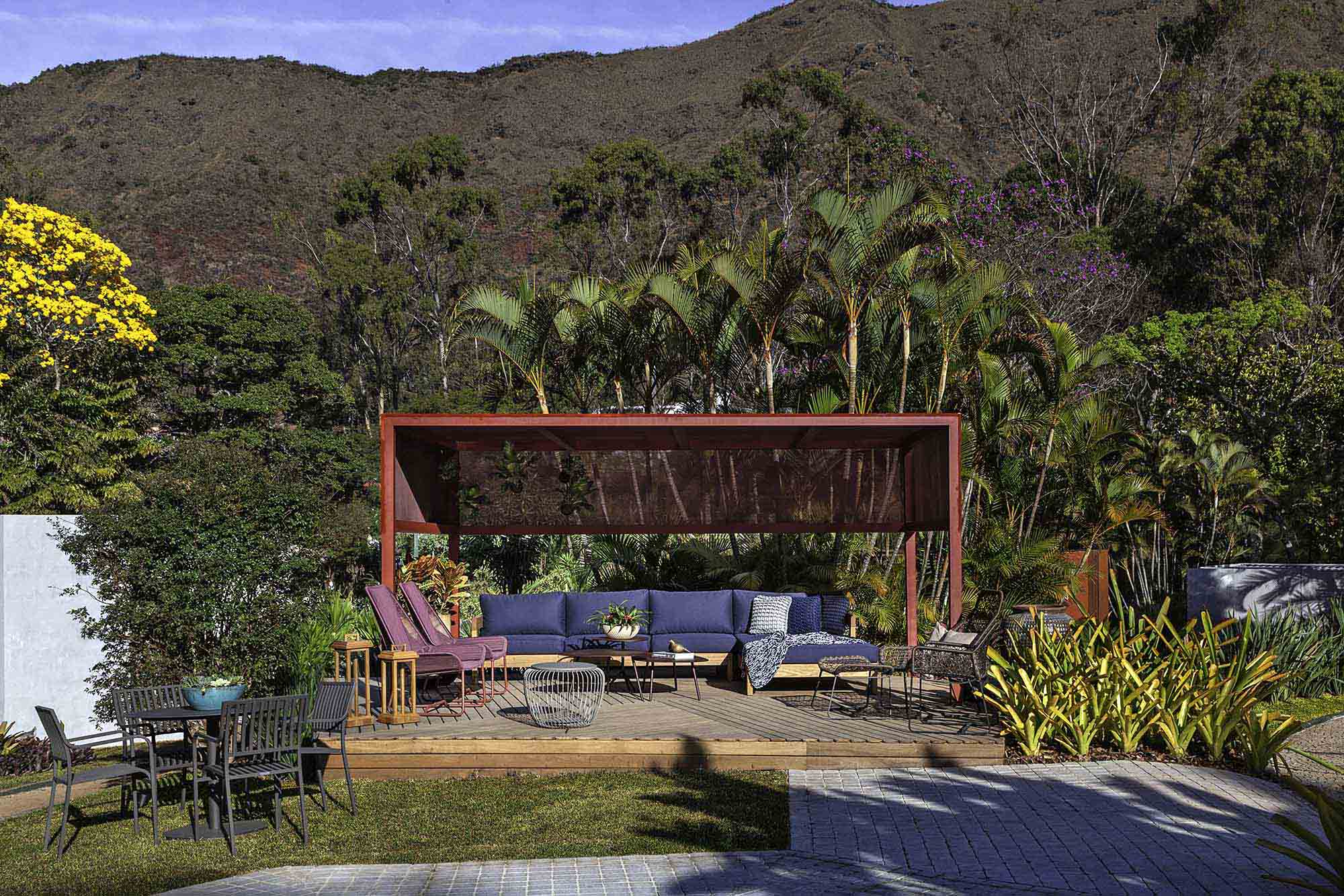 Duppio Design – Espaço do Encontro. O deck de madeira se propõe a ser um refúgio para o artista desenvolver seu trabalho, buscar inspiração na paisagem e descansar. O tom de vermelho o destaca do cenário da Serra do Curral, complementado pelo verde do jardim de Andreia Campolina.