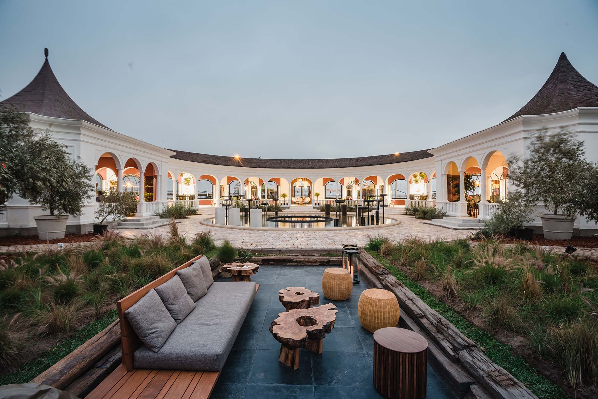 Restaurante La Cuadra de Salvador - Olenka Marquina. A estrutura de 1930 é transformada em restaurante com toques de modernidade e funcionalidade. O conjunto de arcos que abraça o espaço inspirou a geometria de estruturas em ferro que delimitam pequenos ambientes internos. A iluminação ressalta a elegância da arquitetura e colabora com a atmosfera sofisticada. Em primeiro plano, o lounge acolhe e combina texturas naturais, como a madeira bruta e as fibras.