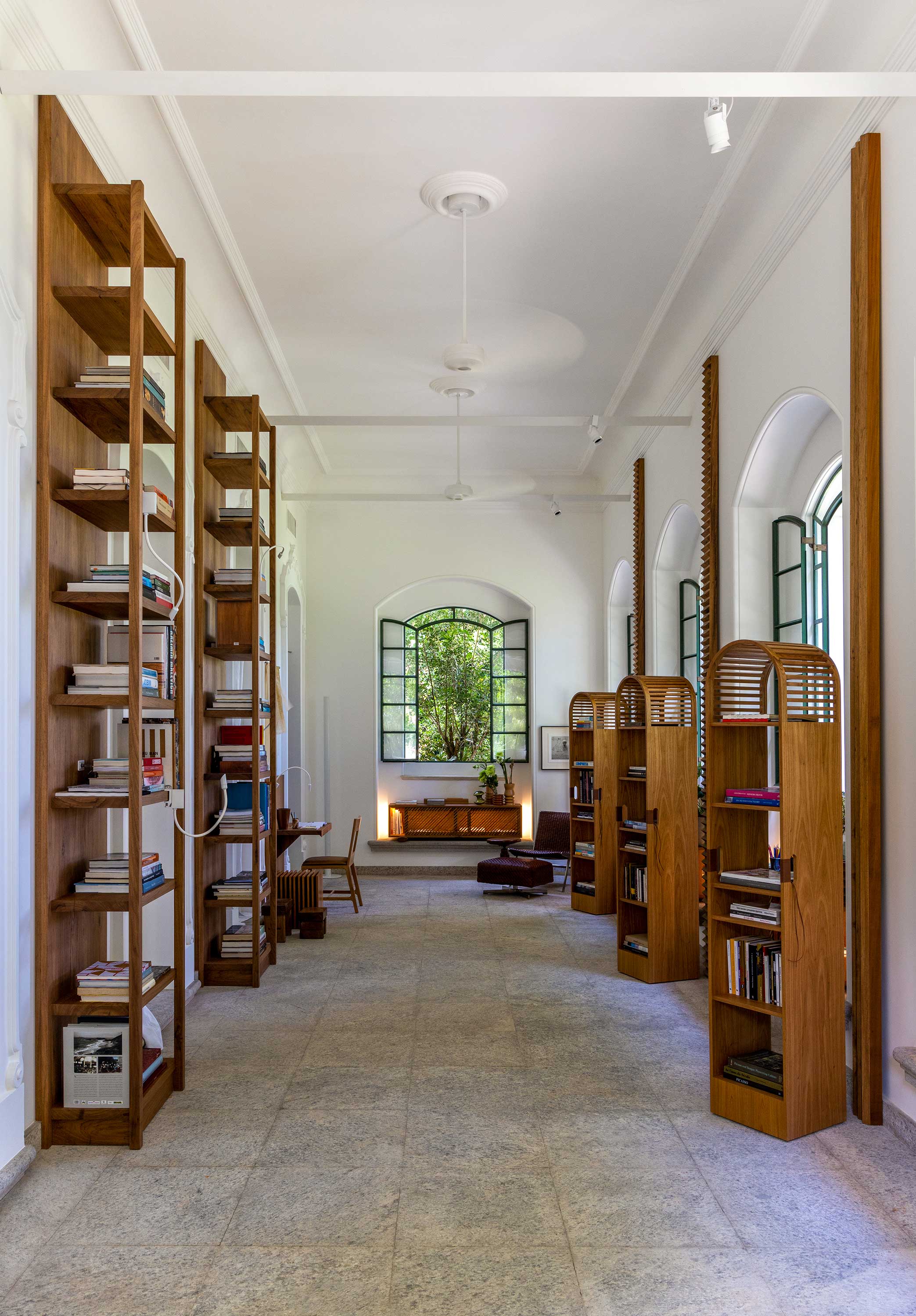 Espaço III Pequena Sala de Estudos - CASACOR Rio de Janeiro 2021. Solar com janelas generosas e pé-direito alto, o projeto tira proveito da arquitetura original e aposta no branco como rebatedor da luz natural e fonte de frescor, sossego e simplicidade. O mobiliário e a marcenaria assinados por Lia utilizam materiais naturais que dialogam com o piso de pedras de cantaria e com os jardins visíveis pelas janelas.